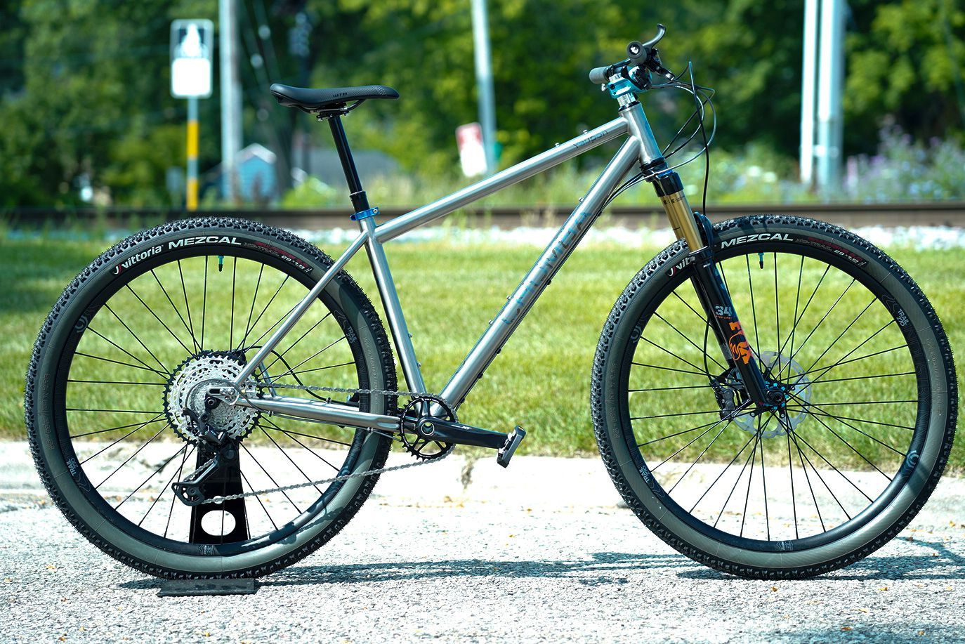 A bicycle is parked on the side of the road next to a grassy field.