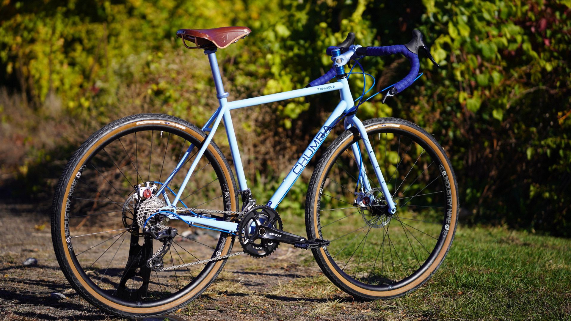 A blue bicycle is parked on the side of a dirt road.