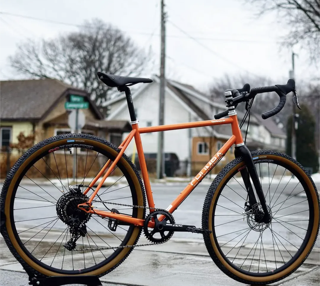 An orange bicycle is parked on the side of the road
