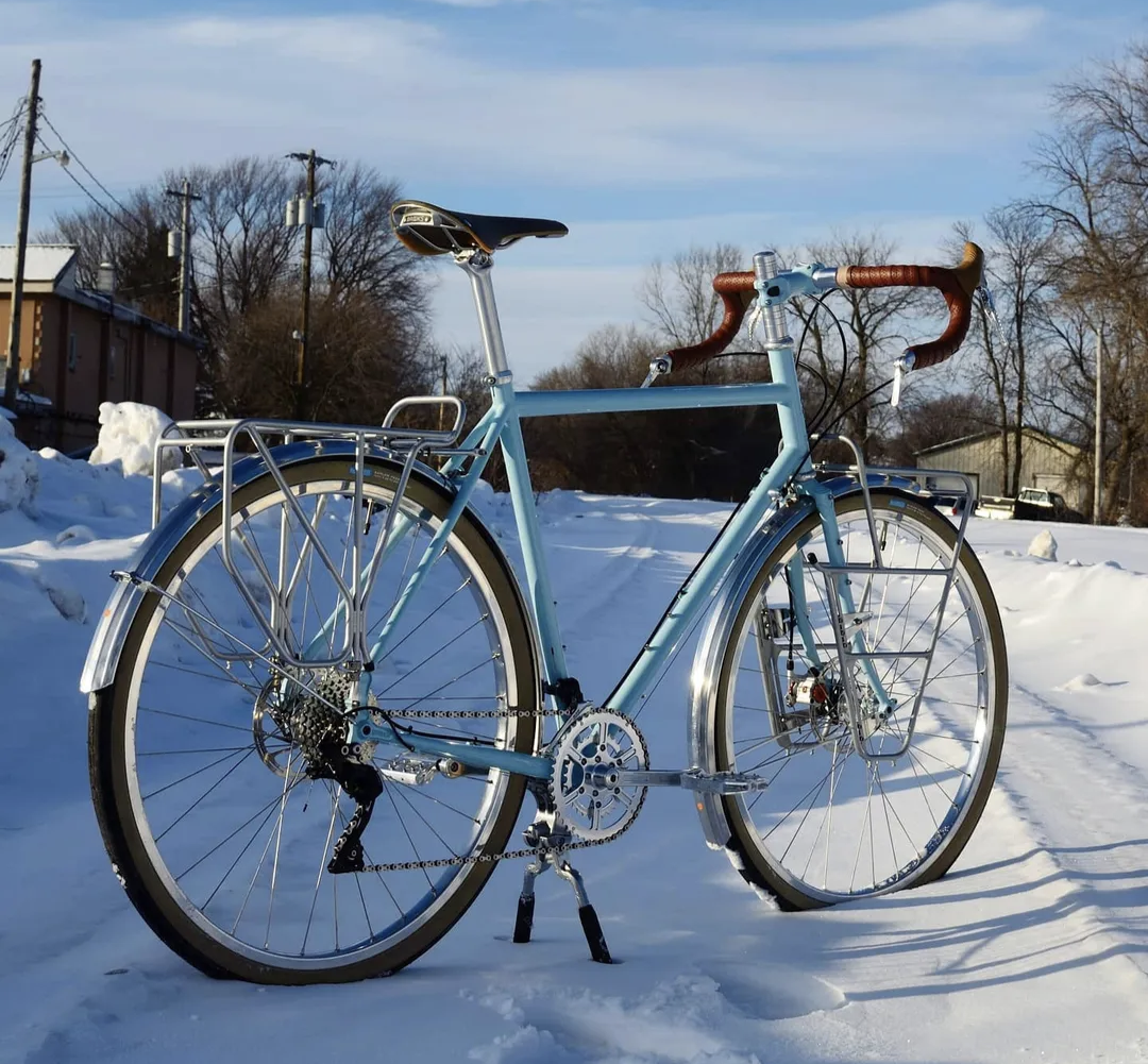 A blue bicycle is parked on a snowy road