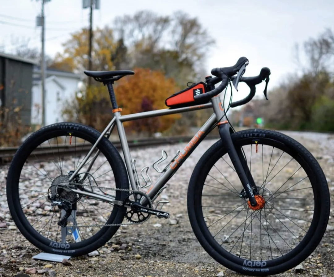 A bicycle is parked on the side of a train track.