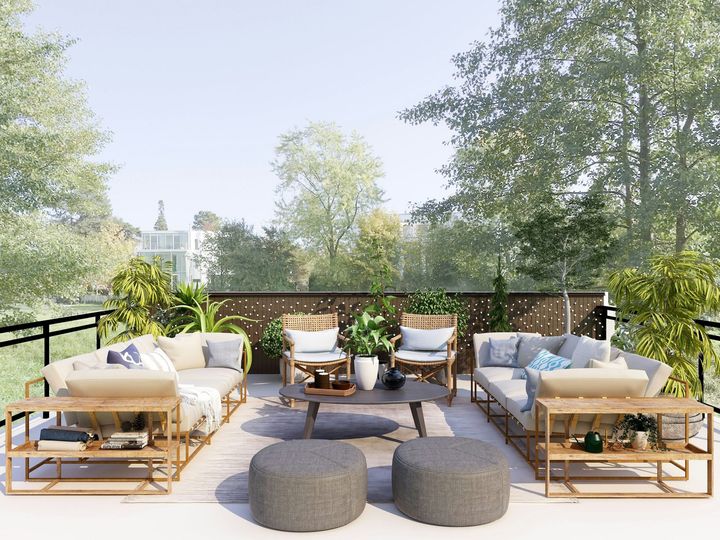 Outdoor patio with beige sofas, round ottomans, and chairs around a fire pit surrounded by trees