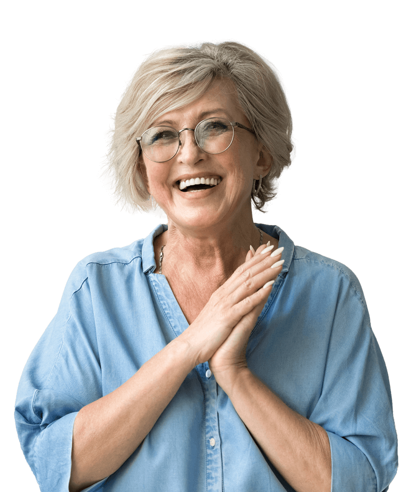 An older woman wearing glasses and a blue shirt is smiling with her hands on her chest.