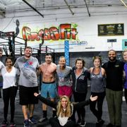 A group of people standing and smiling in a gym in front of a graffiti-style 