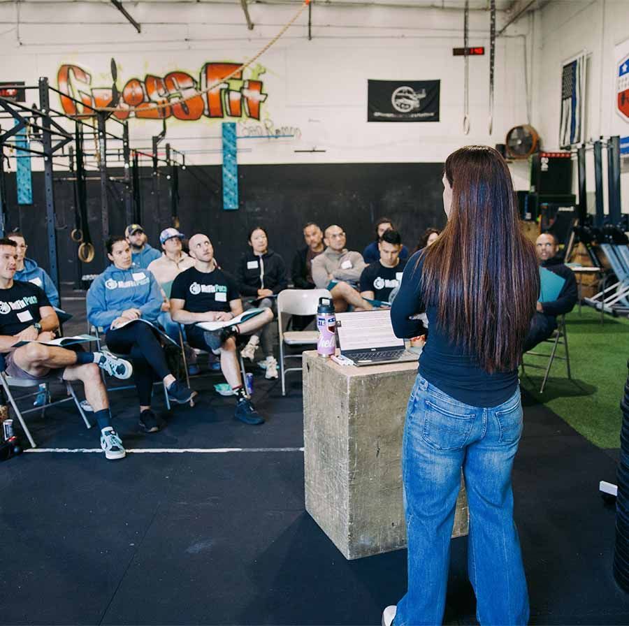 People lifting barbells in a CrossFit gym during a group fitness class.