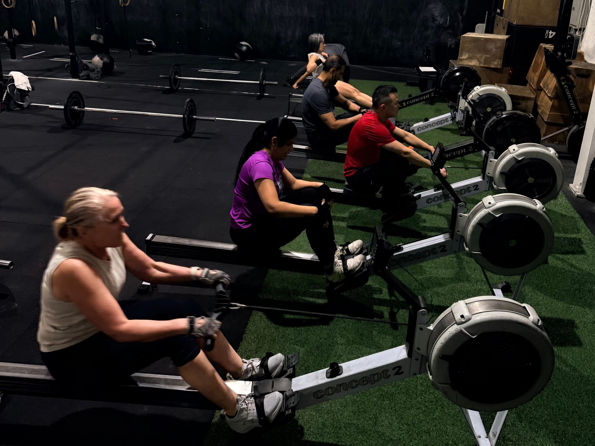 An instructor leads a workshop for a seated group in a gym with CrossFit branding on the wall.