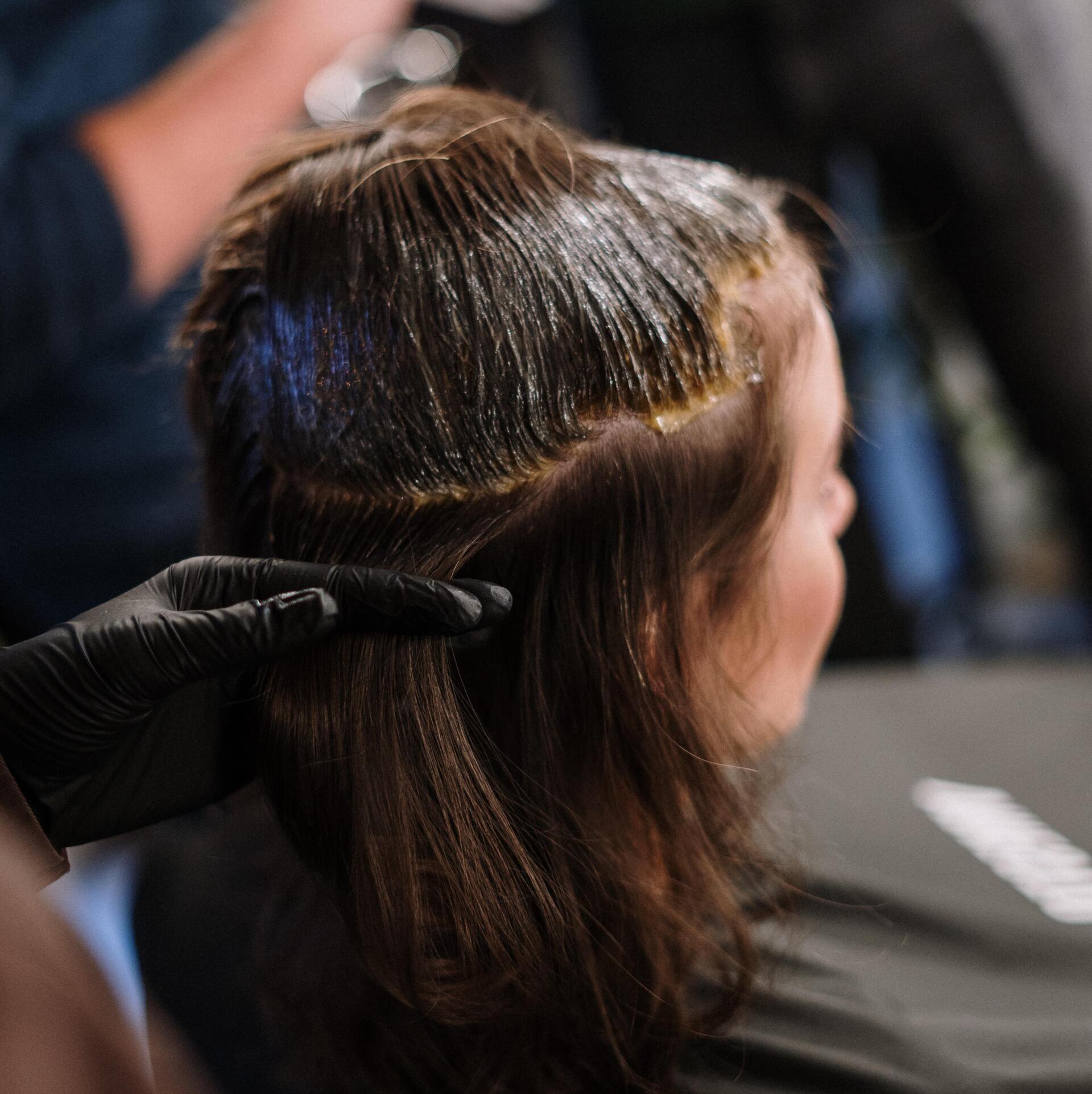A woman is getting her hair dyed by a hairdresser.