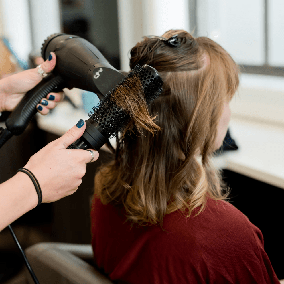 A woman is getting her hair blow dried in a salon.