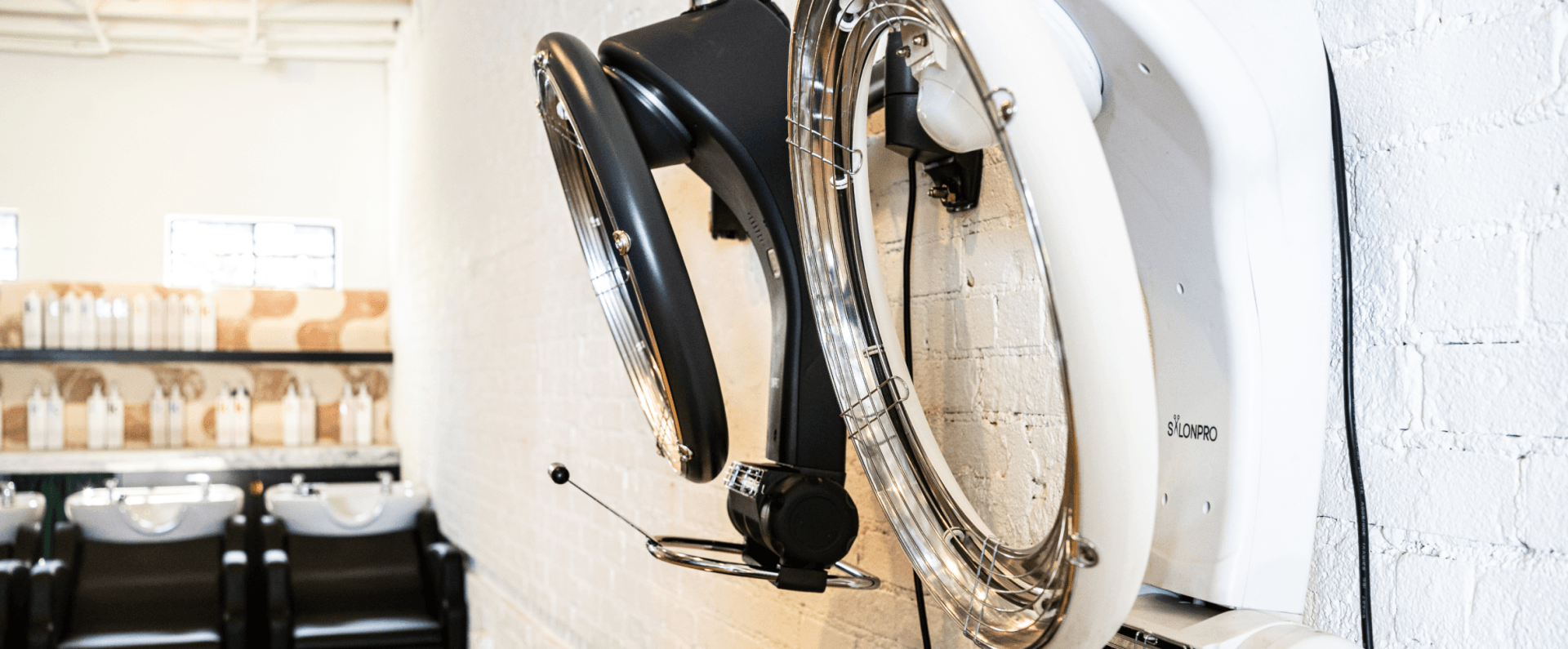 A hair dryer is hanging on a wall in a salon.