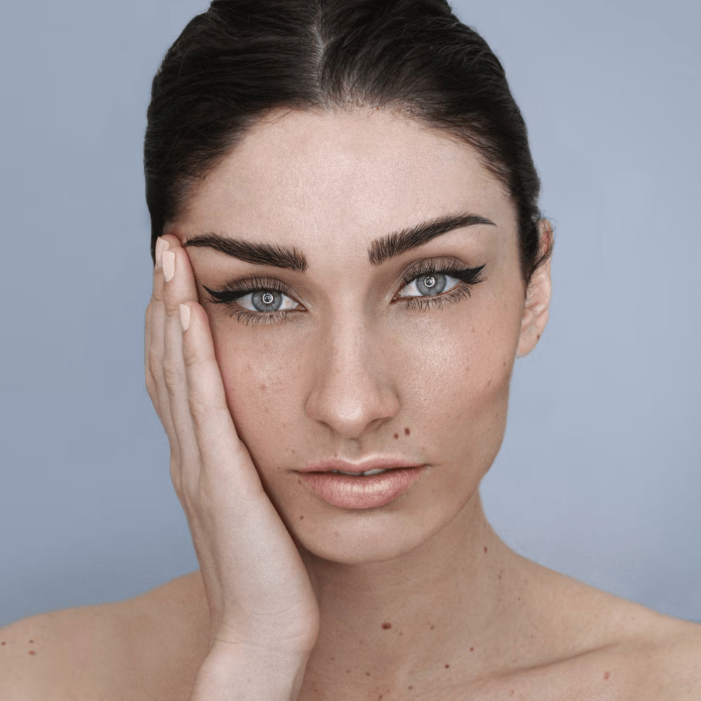 A close up of a woman 's face with her hand on her face