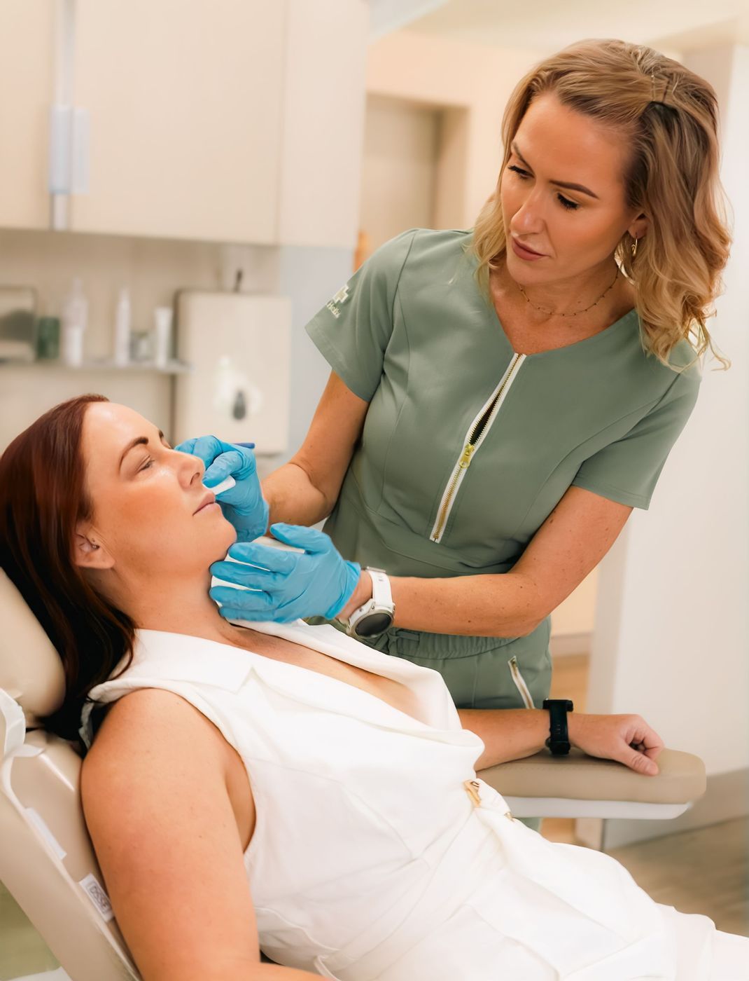 Woman getting facial injections from a medical professional in a clinic.