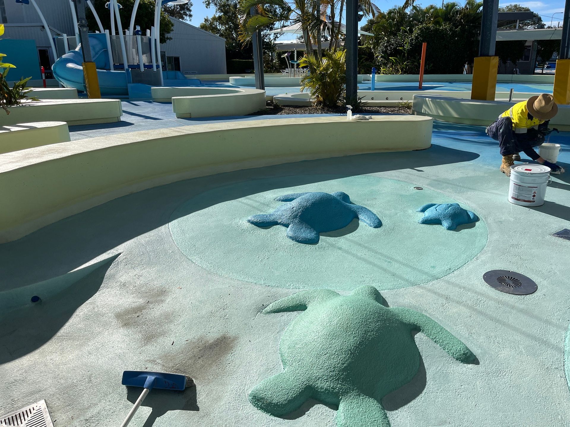 A Worker Paints Sea Turtle Shapes Onto a Blue Aquatic Playground Surface — Priority Painters in Gladstone Central, QLD