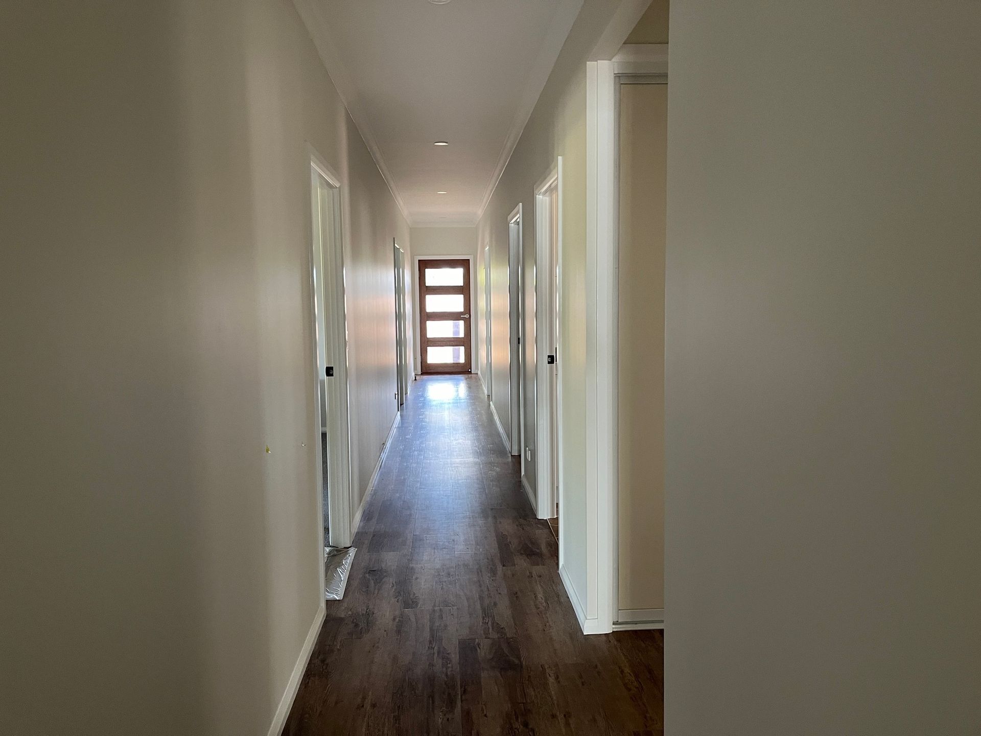 A Long, Narrow Hallway With Light-colored Walls and Dark Wood Flooring — Priority Painters in Gladstone Central, QLD
