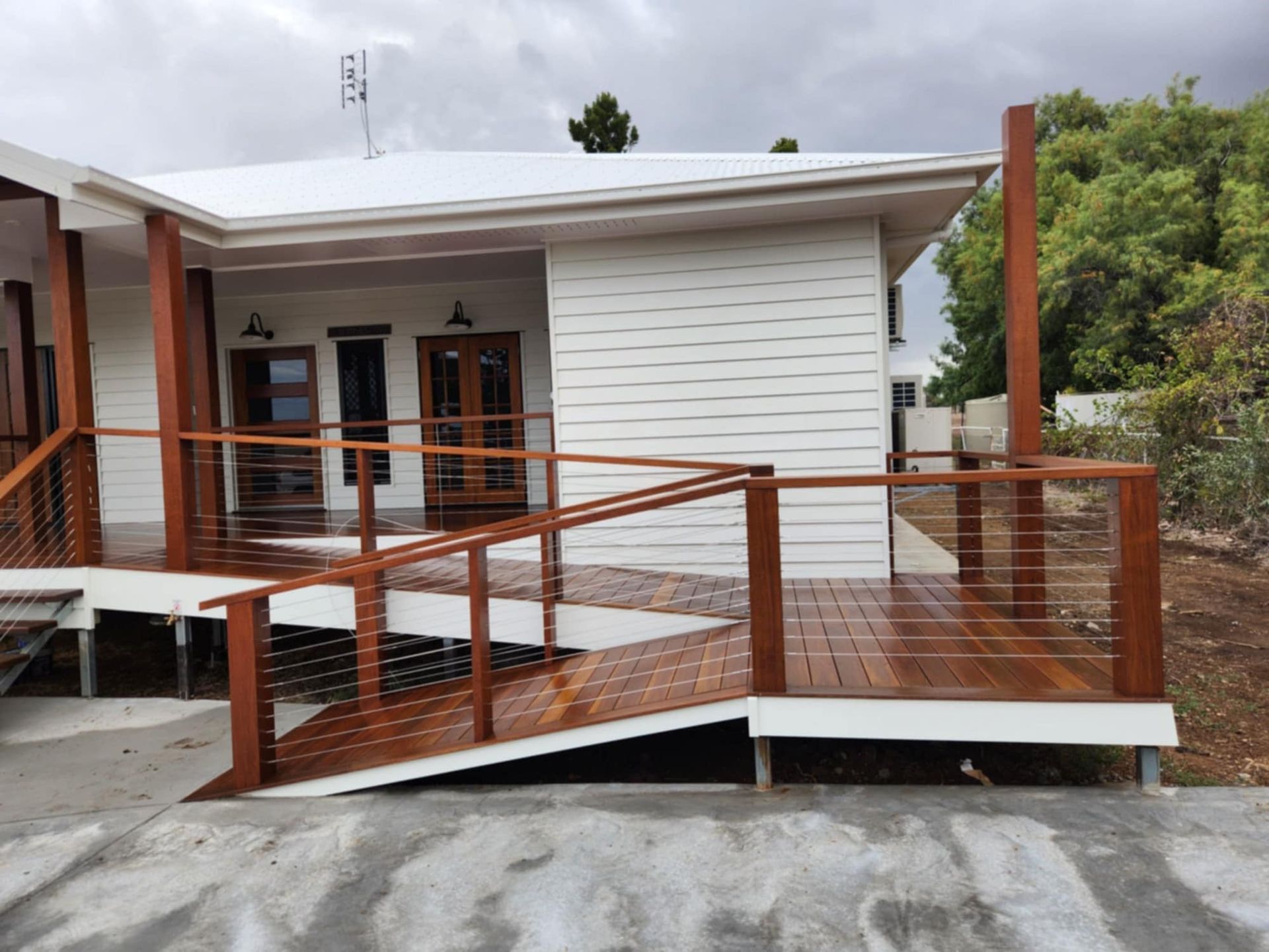 A Wooden Wheelchair Ramp With Metal Railings — Priority Painters in Gladstone Central, QLD