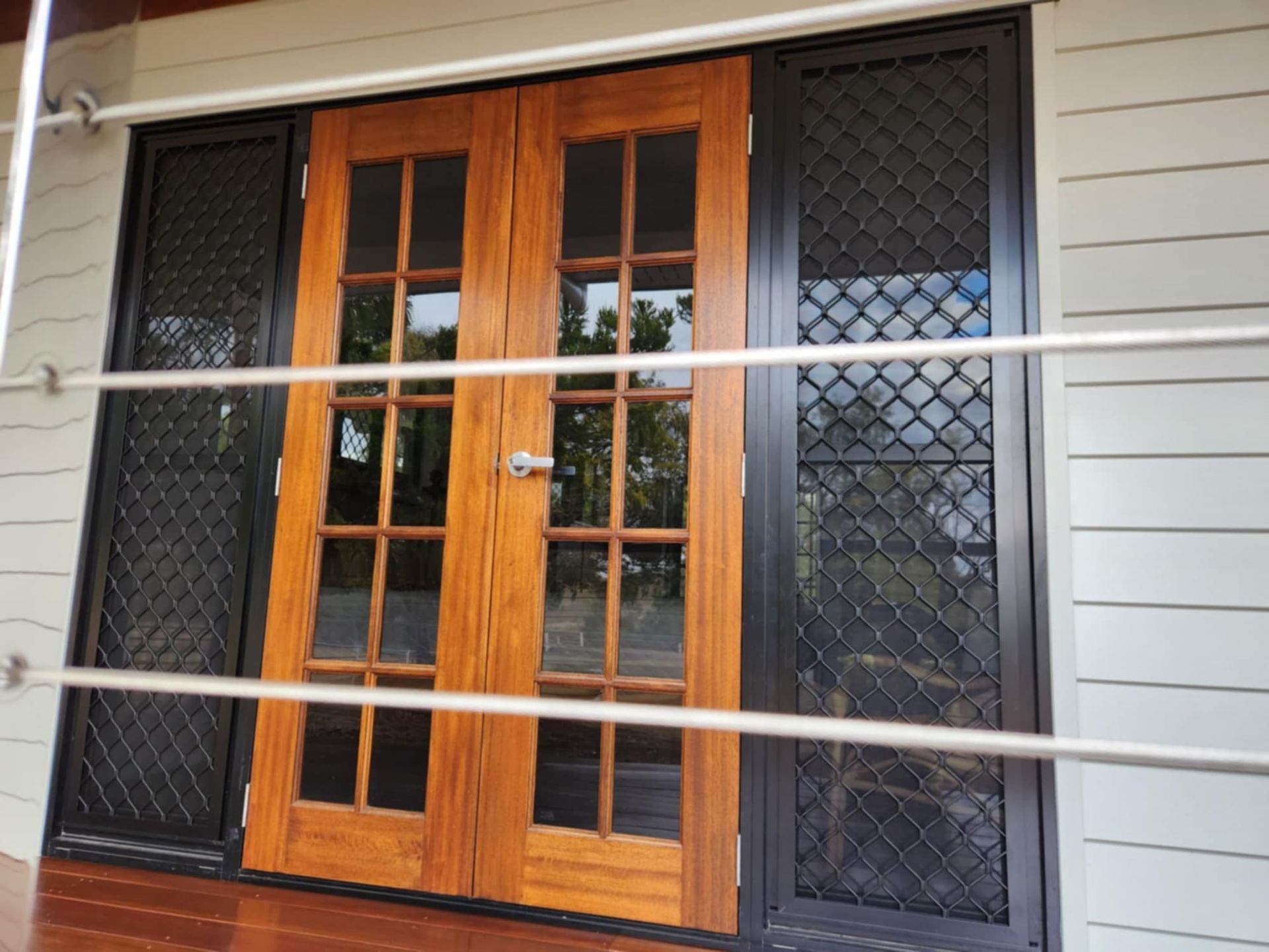 Wooden Double French Doors Flanked by Black Security Screen Doors — Priority Painters in Gladstone Central, QLD