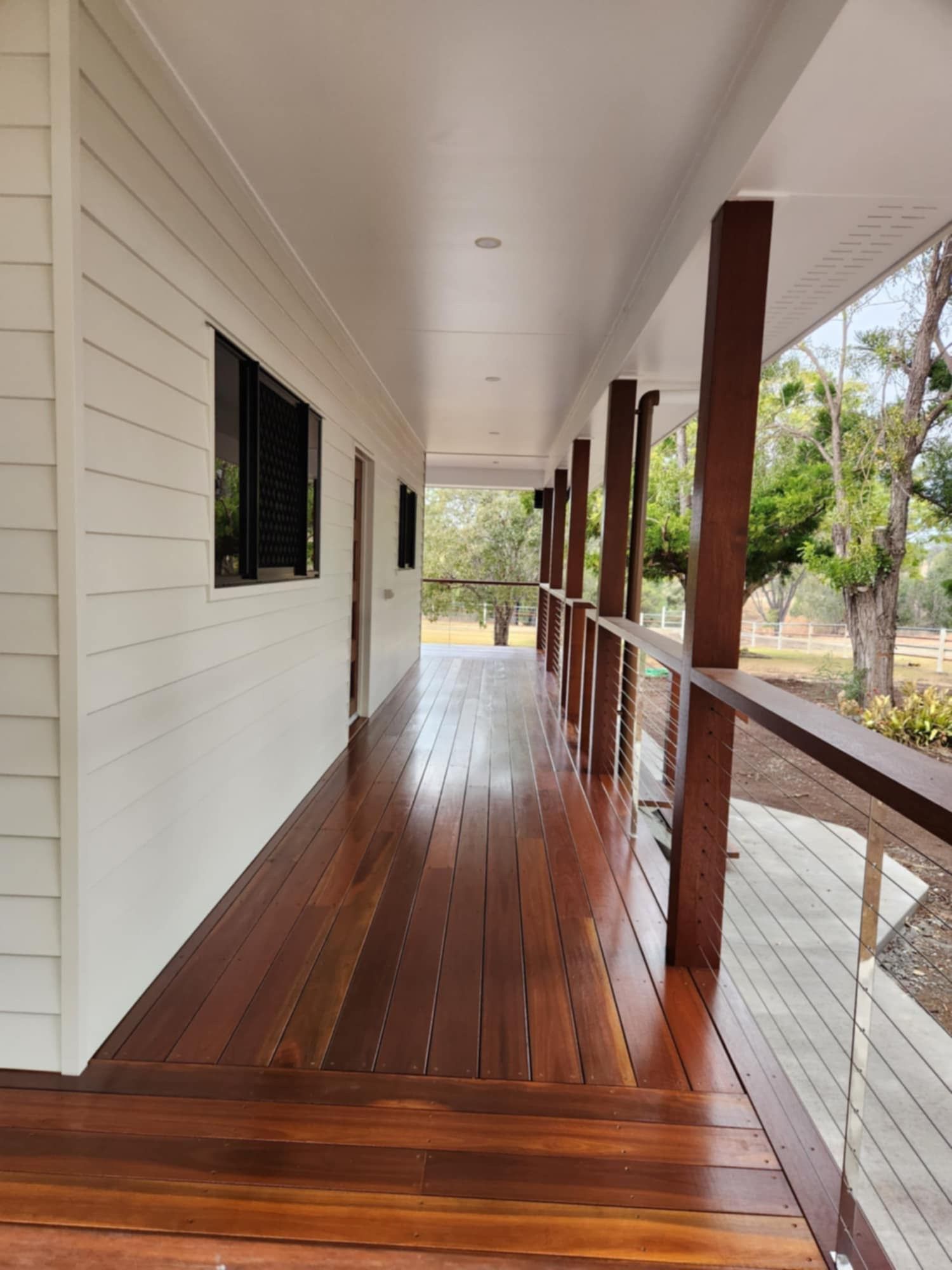 A Long, Narrow Wooden Deck With a White Wall and a Modern Railing — Priority Painters in Gladstone Central, QLD