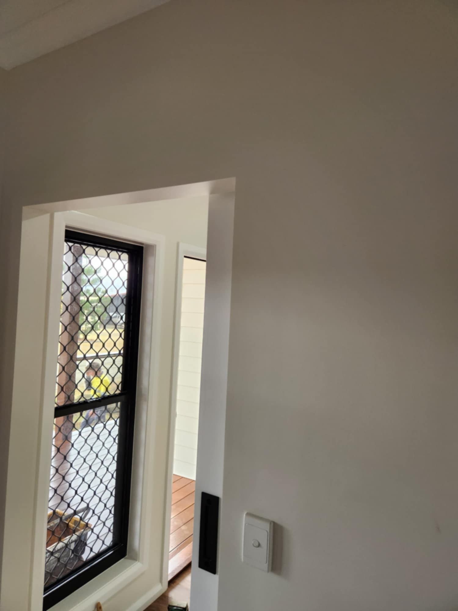 A View Through a White Doorway Showing a Window With a Black Security Screen — Priority Painters in Gladstone Central, QLD