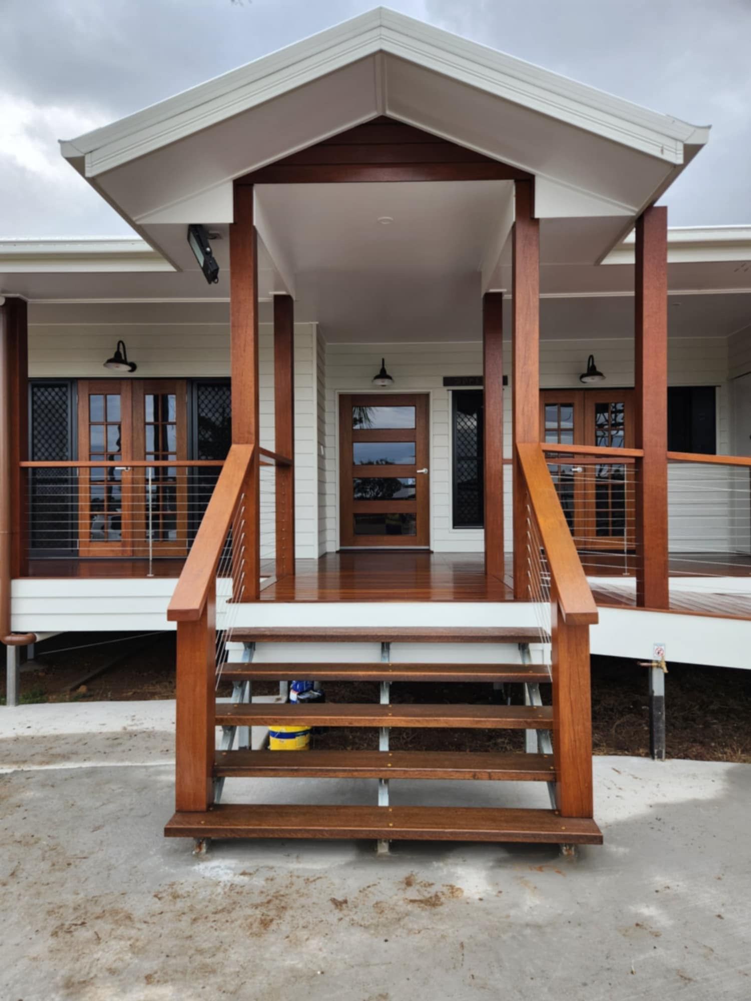 A Wooden Staircase With Metal Handrails Leading to the Covered Porch — Priority Painters in Gladstone Central, QLD
