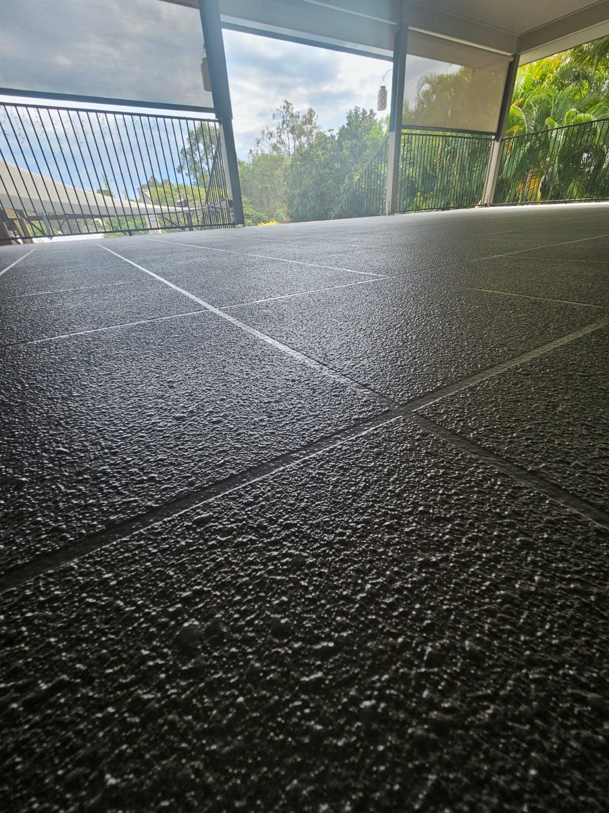 A Dark Grey, Textured Patio Floor With Grid-like Score Lines — Priority Painters in Gladstone Central, QLD