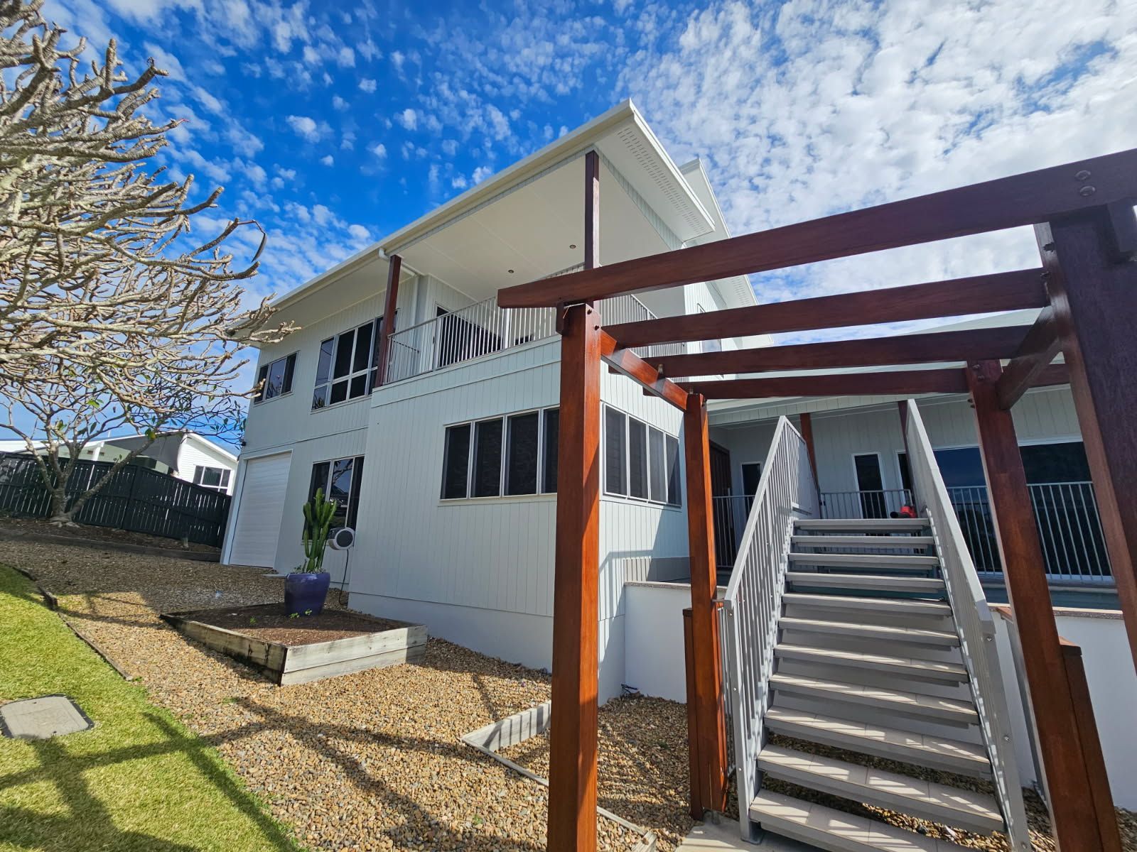 A Two-story White House With a Wooden Pergola — Priority Painters in Gladstone Central, QLD