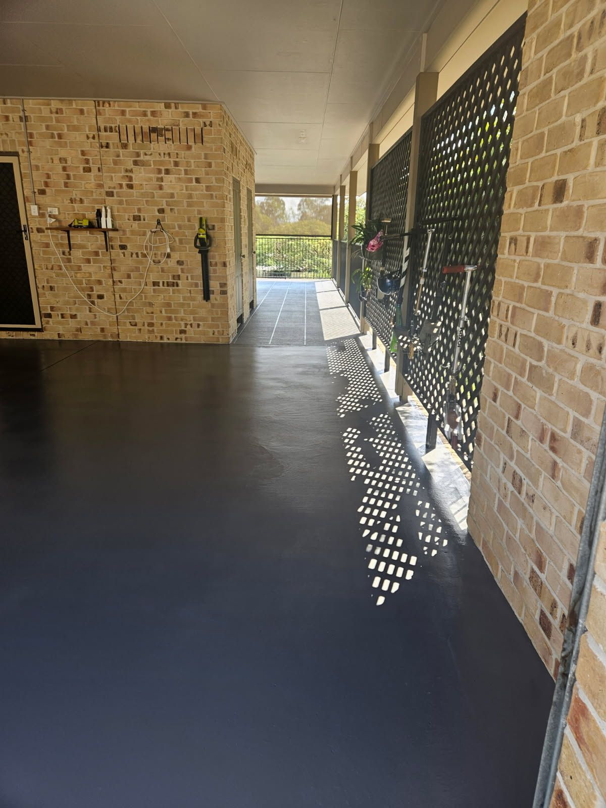A Covered Outdoor Patio With a Dark Grey Floor, Light Brick Walls — Priority Painters in Gladstone Central, QLD