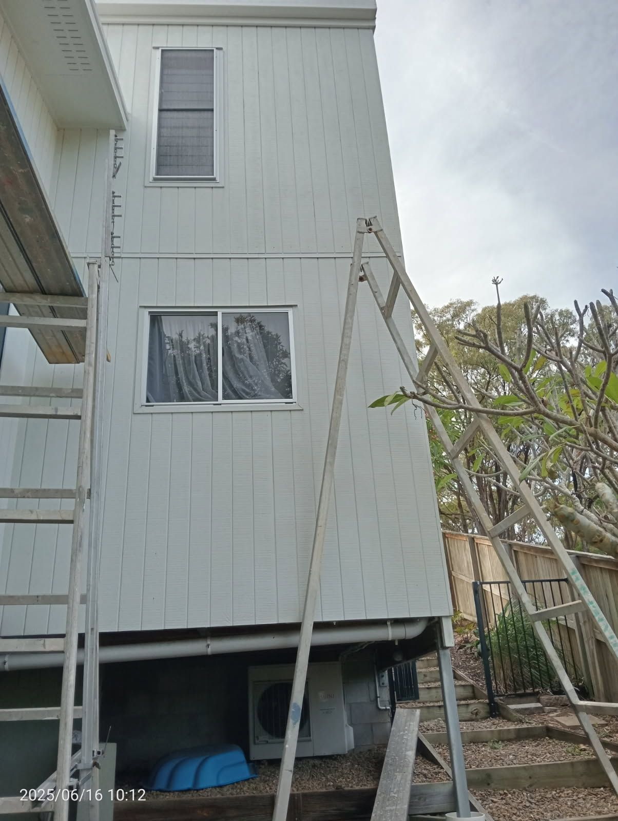 Two Ladders Lean Against the White Vertical Siding — Priority Painters in Gladstone Central, QLD