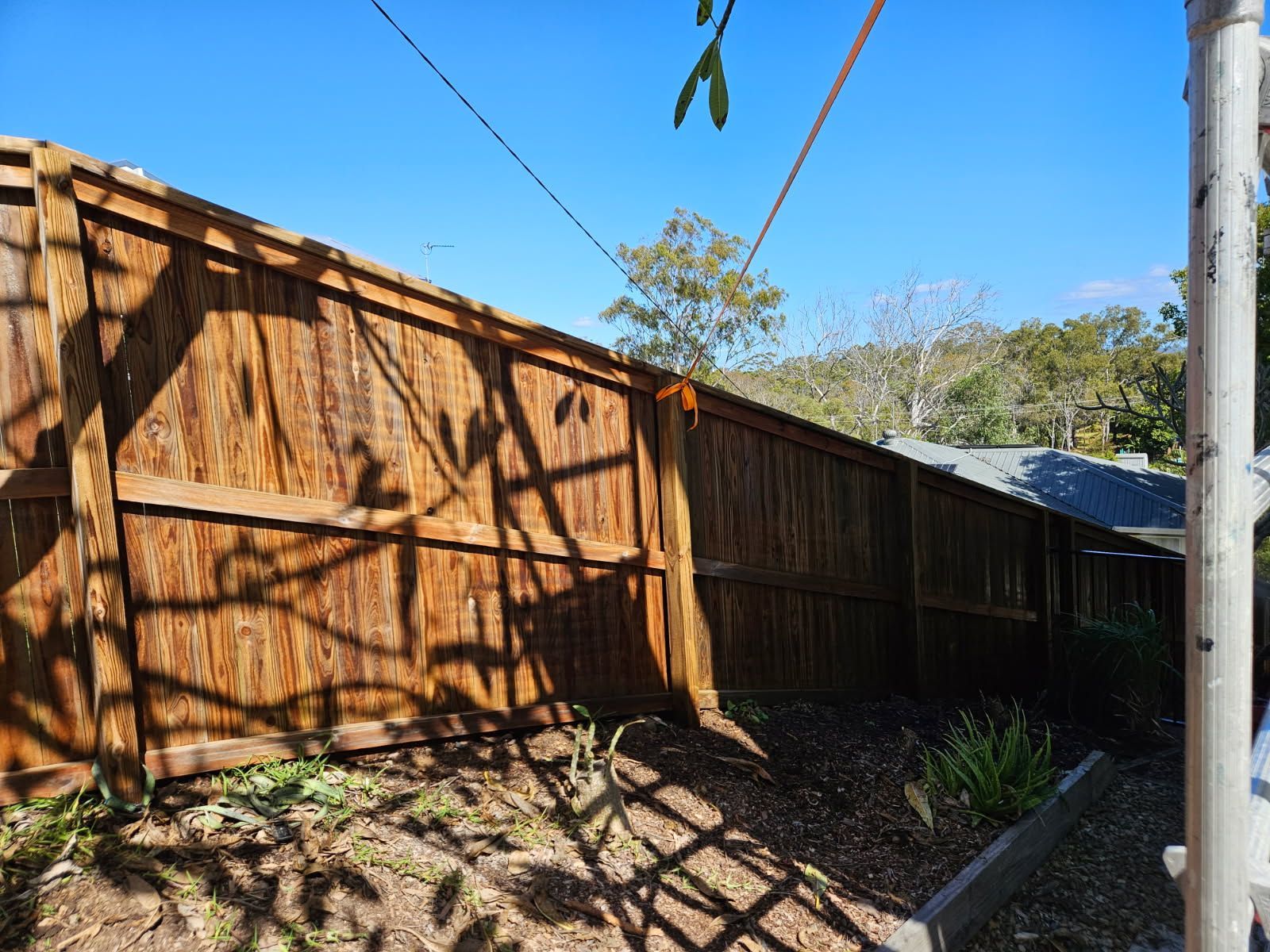 A Wooden Fence Runs Diagonally Across a Sunny Yard — Priority Painters in Gladstone Central, QLD