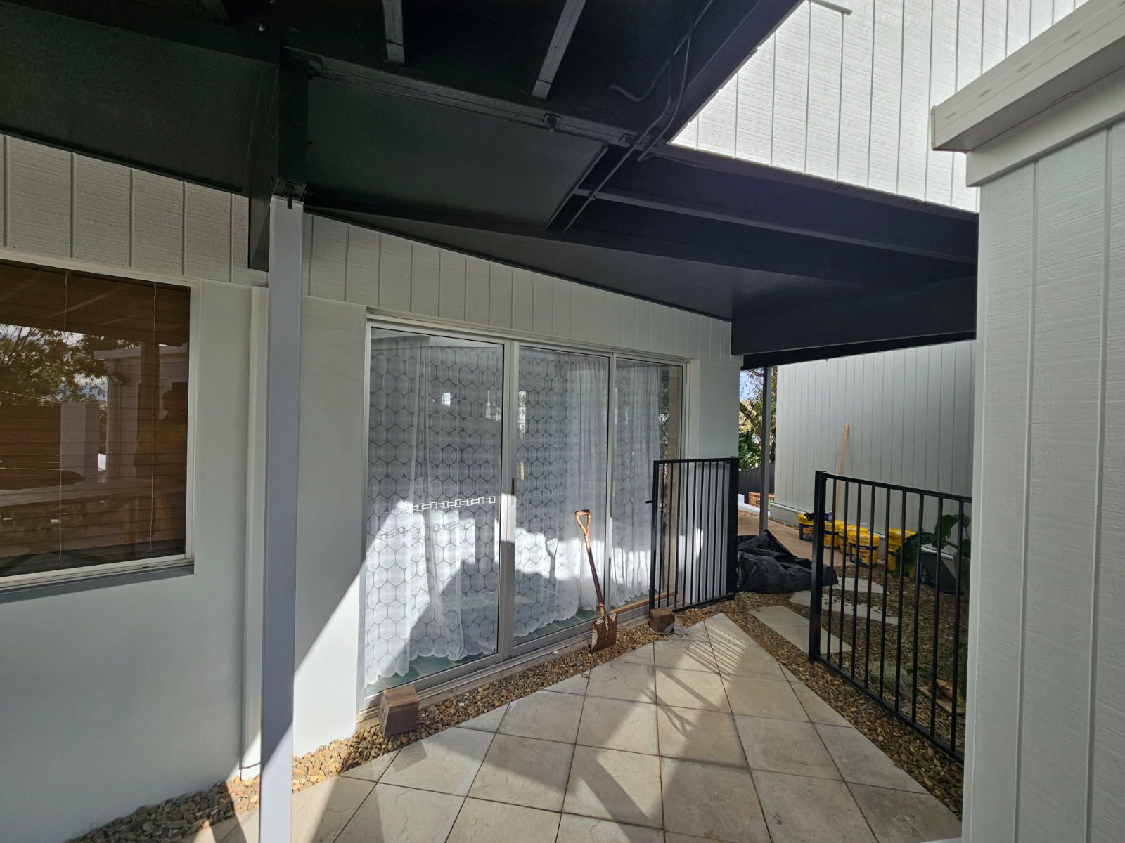 A Covered Concrete Patio With White Walls, a Sliding Glass Door — Priority Painters in Gladstone Central, QLD