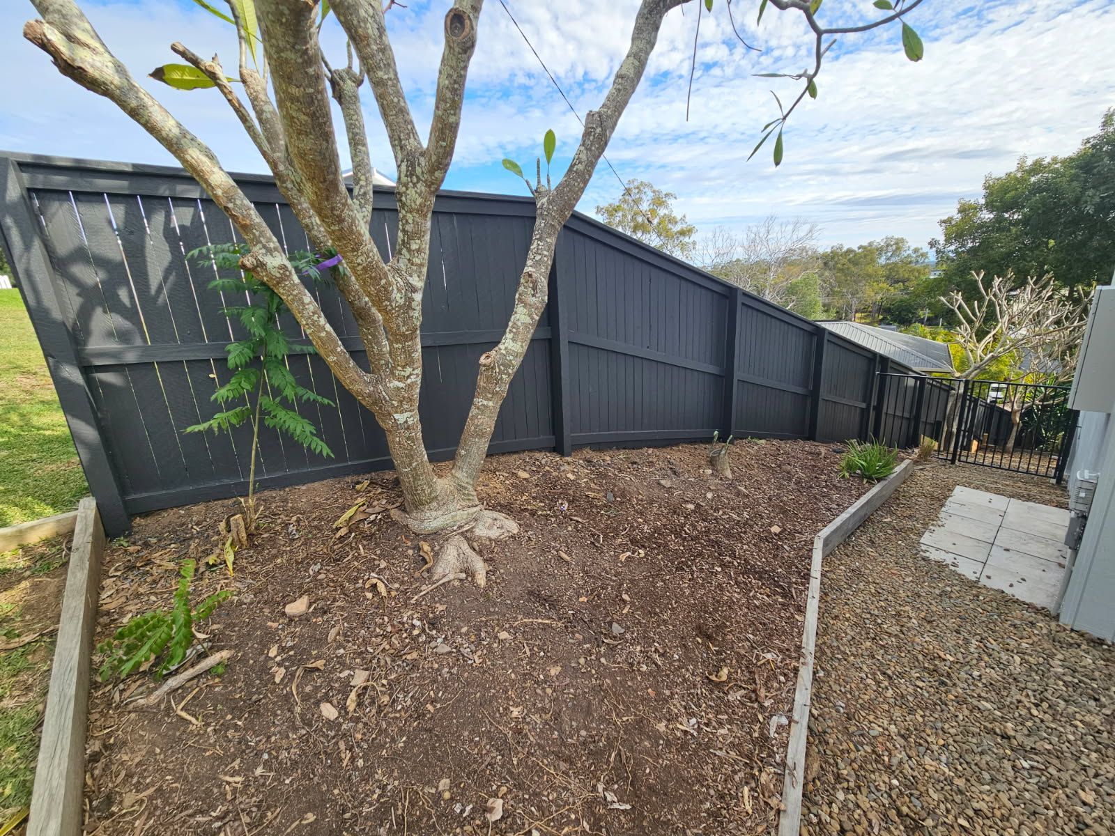 A Dark Wooden Fence Slopes Downward Along a Landscaped Garden — Priority Painters in Gladstone Central, QLD