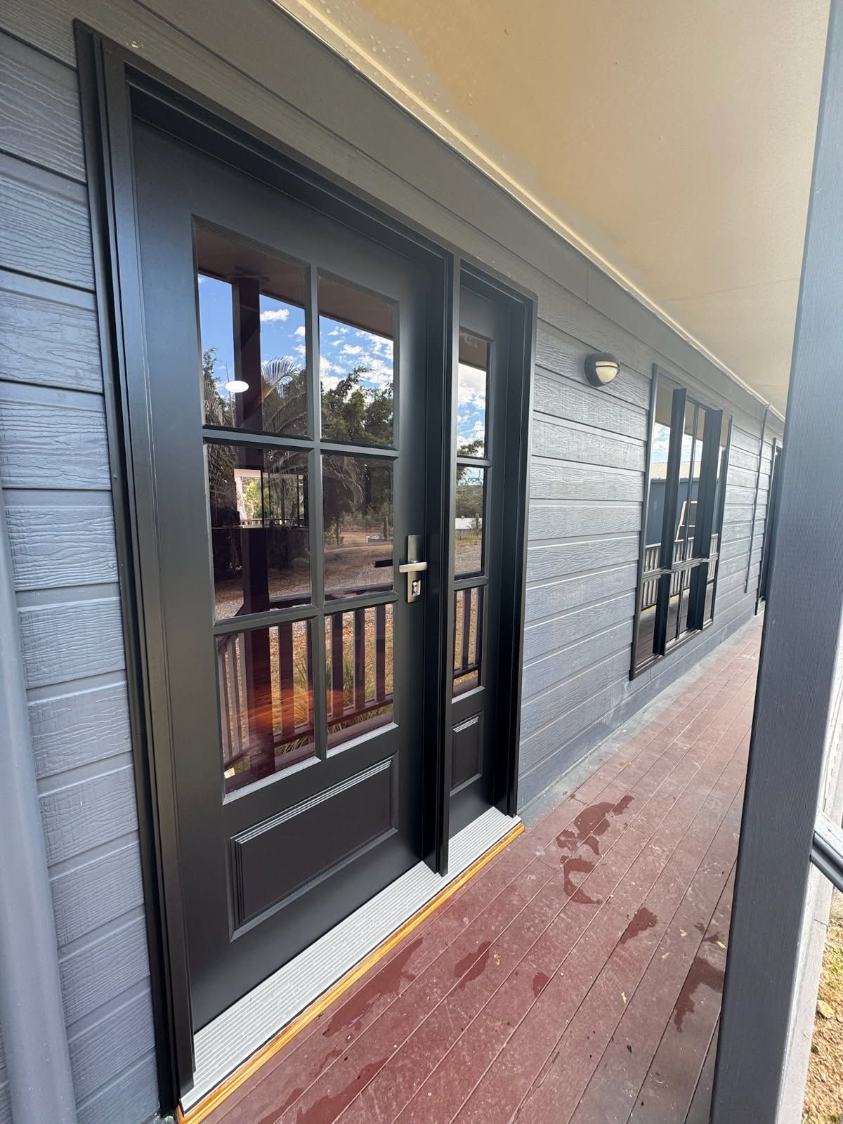 A Dark Grey Door With Glass Panes and a Side Panel on a Porch — Priority Painters in Gladstone Central, QLD