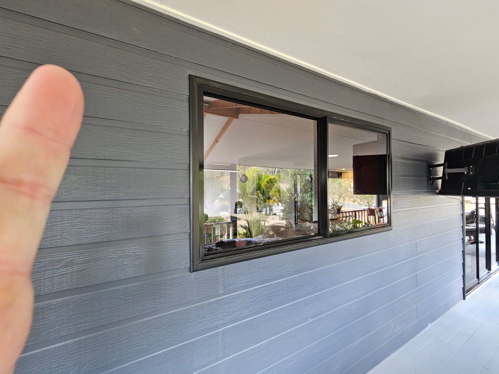 A Finger Points to Textured, Dark Grey Horizontal Cladding — Priority Painters in Gladstone Central, QLD