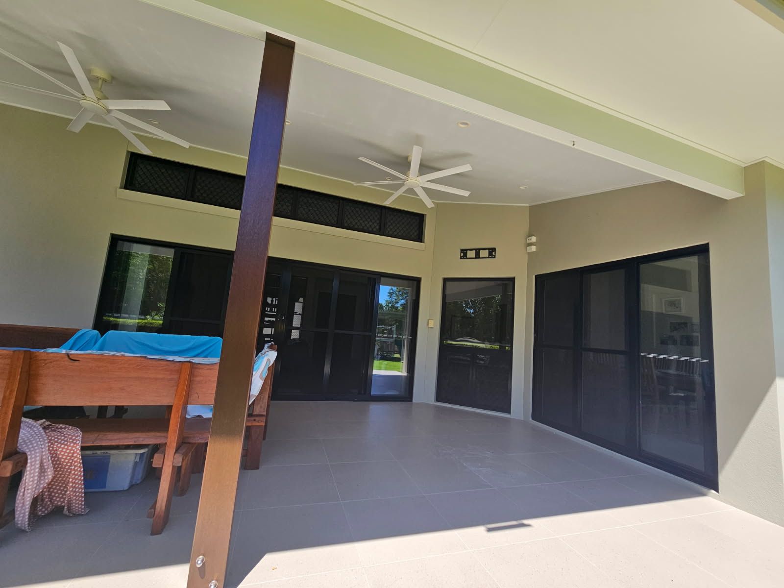 A Spacious Covered Patio With Tile Flooring, and Two Ceiling Fans — Priority Painters in Gladstone Central, QLD