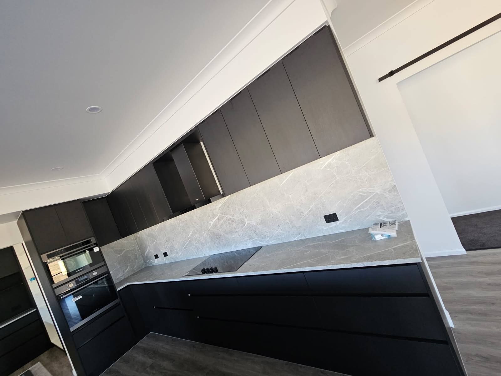 A Modern Kitchen With Dark Grey Cabinets, Light Marble Countertops — Priority Painters in Gladstone Central, QLD