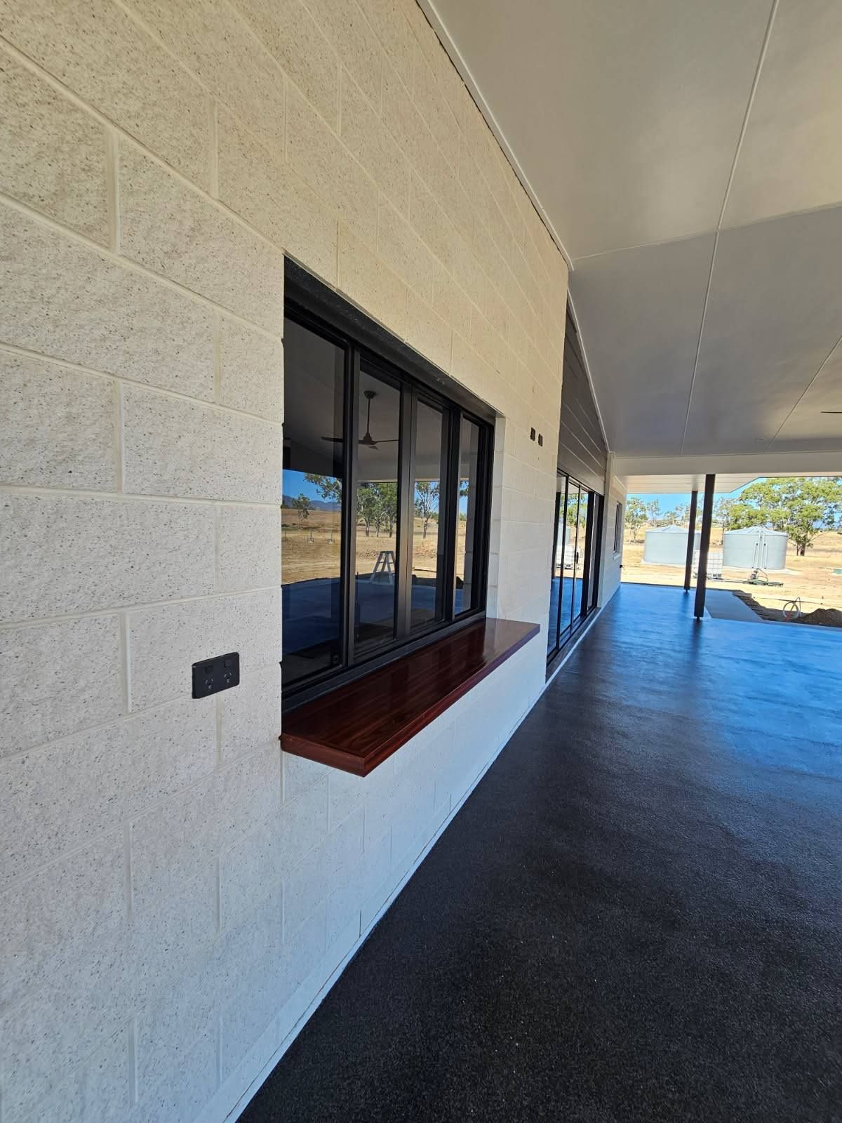A Light-colored Textured Brick Wall With a Black Window Frame — Priority Painters in Gladstone Central, QLD