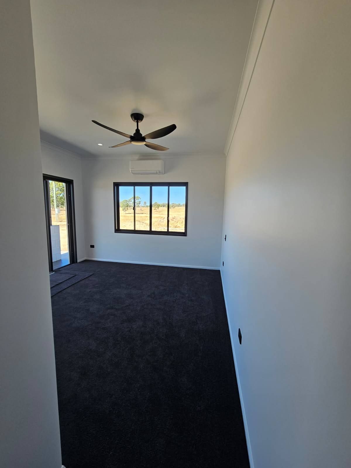 A Bright, Empty Room With Dark Carpeting, and a Ceiling Fan — Priority Painters in Gladstone Central, QLD