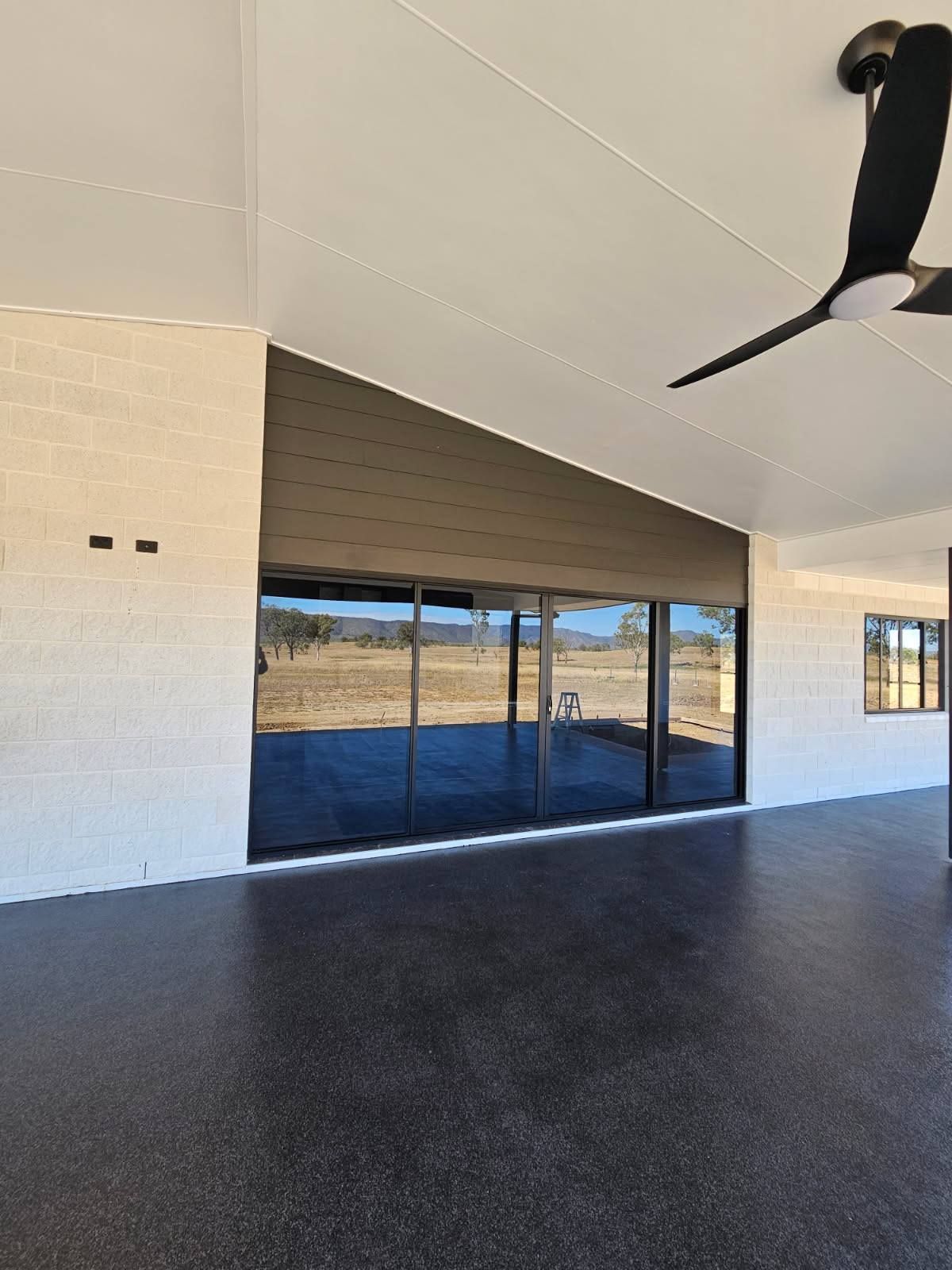 Covered Patio With White Brick Walls, Dark Flooring, and Sliding Glass Doors — Priority Painters in Gladstone Central, QLD