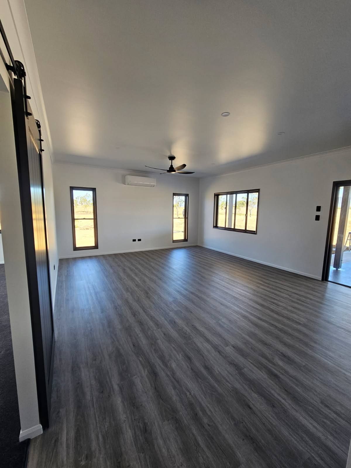 A Spacious, Empty Room With White Walls, and Wood-grain Flooring — Priority Painters in Gladstone Central, QLD