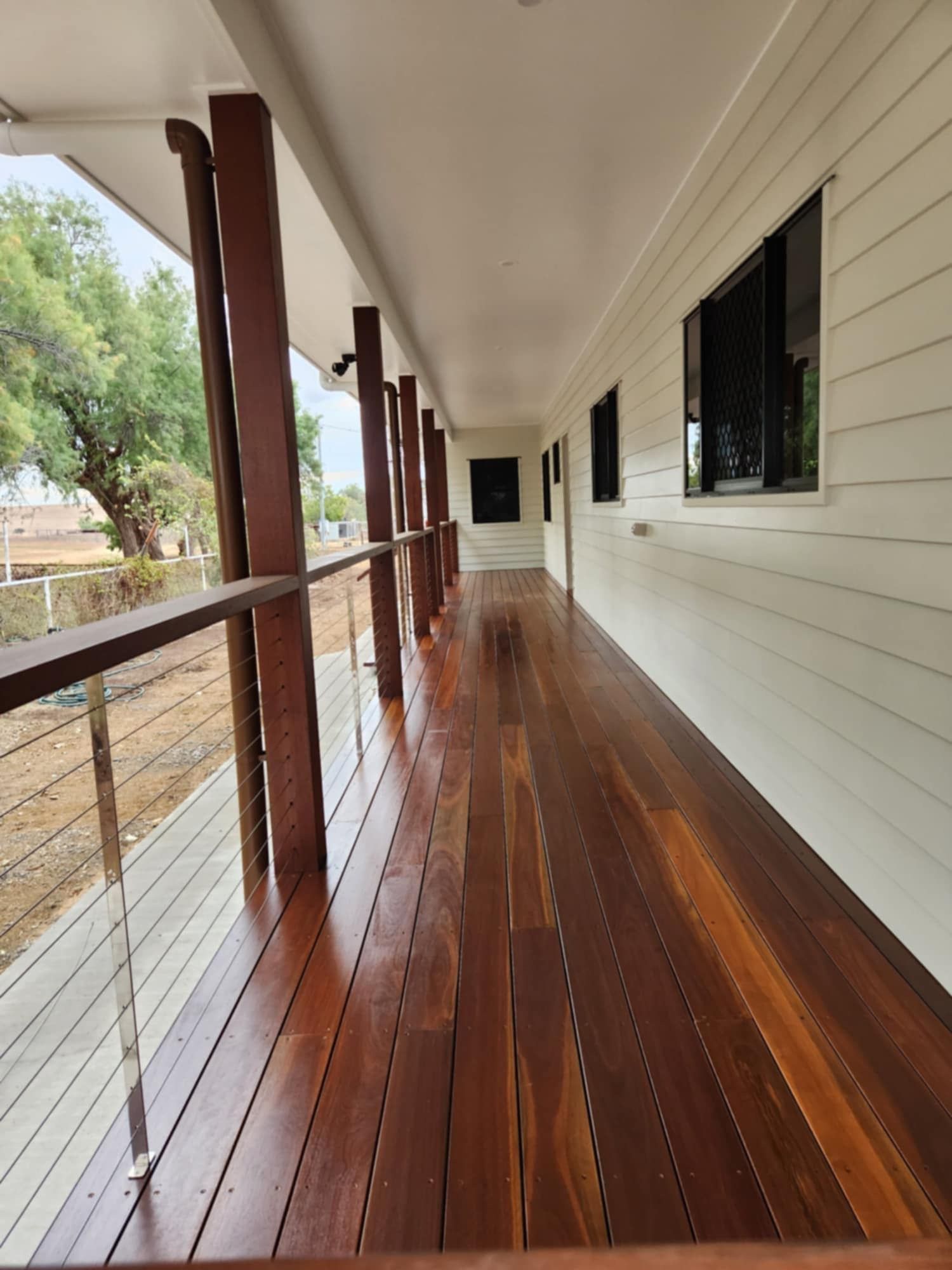 A Wooden Veranda With a Railing and Wire Balustrade — Priority Painters in Gladstone Central, QLD