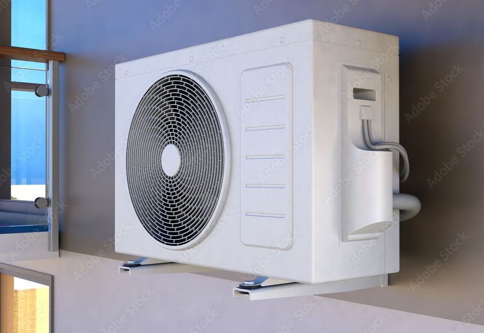 White air conditioning unit mounted on a wall outside, next to a window.