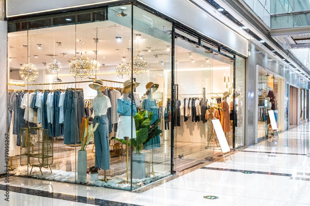 Clothing store storefront with glass windows displaying mannequins and clothing racks.