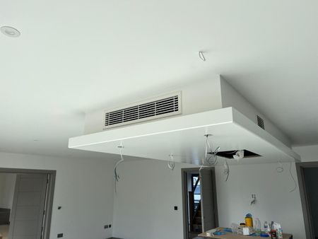 White, unfinished kitchen ceiling with rectangular air vent and exposed wires.