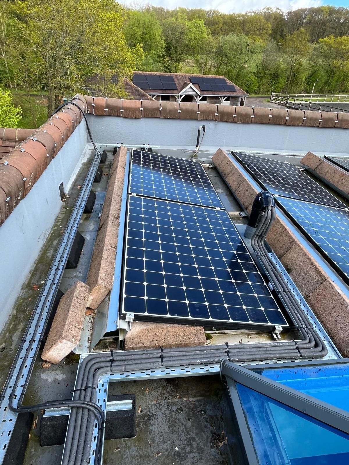 Solar panels installed on a flat rooftop, surrounded by brick edging and electrical wiring.