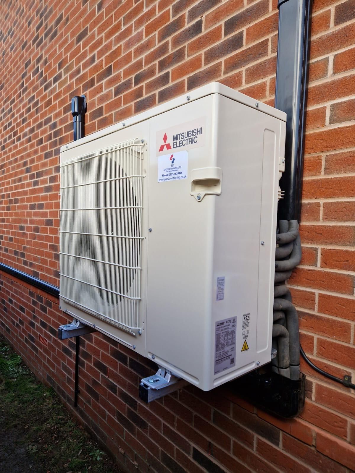 A Mitsubishi air conditioning unit mounted on a brick wall.