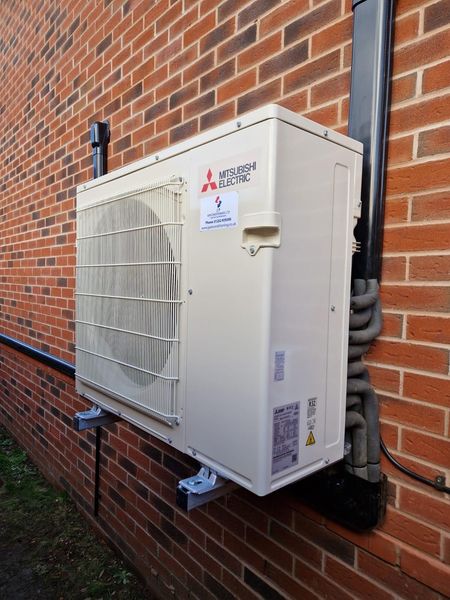 A Mitsubishi air conditioning unit mounted on a brick wall.