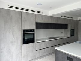 Modern kitchen with gray cabinetry, integrated appliances, and white countertop.