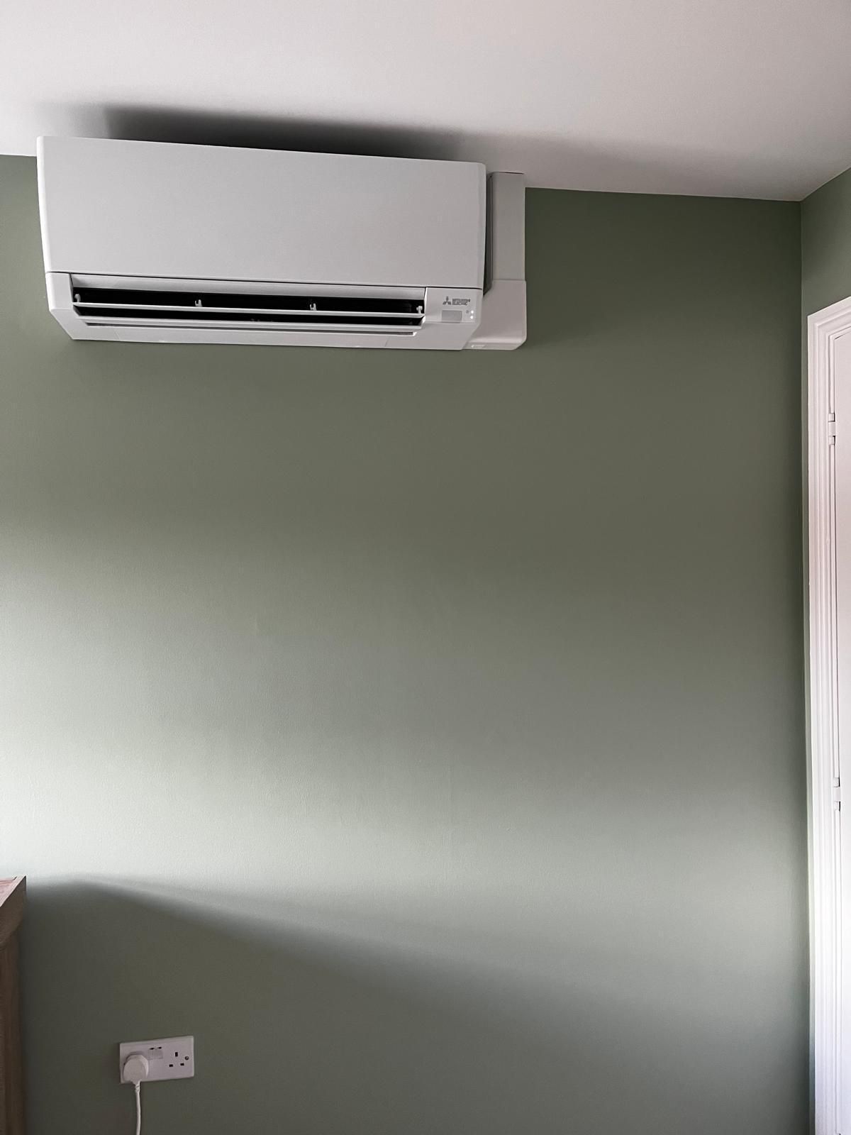 White air conditioning unit on a green wall.