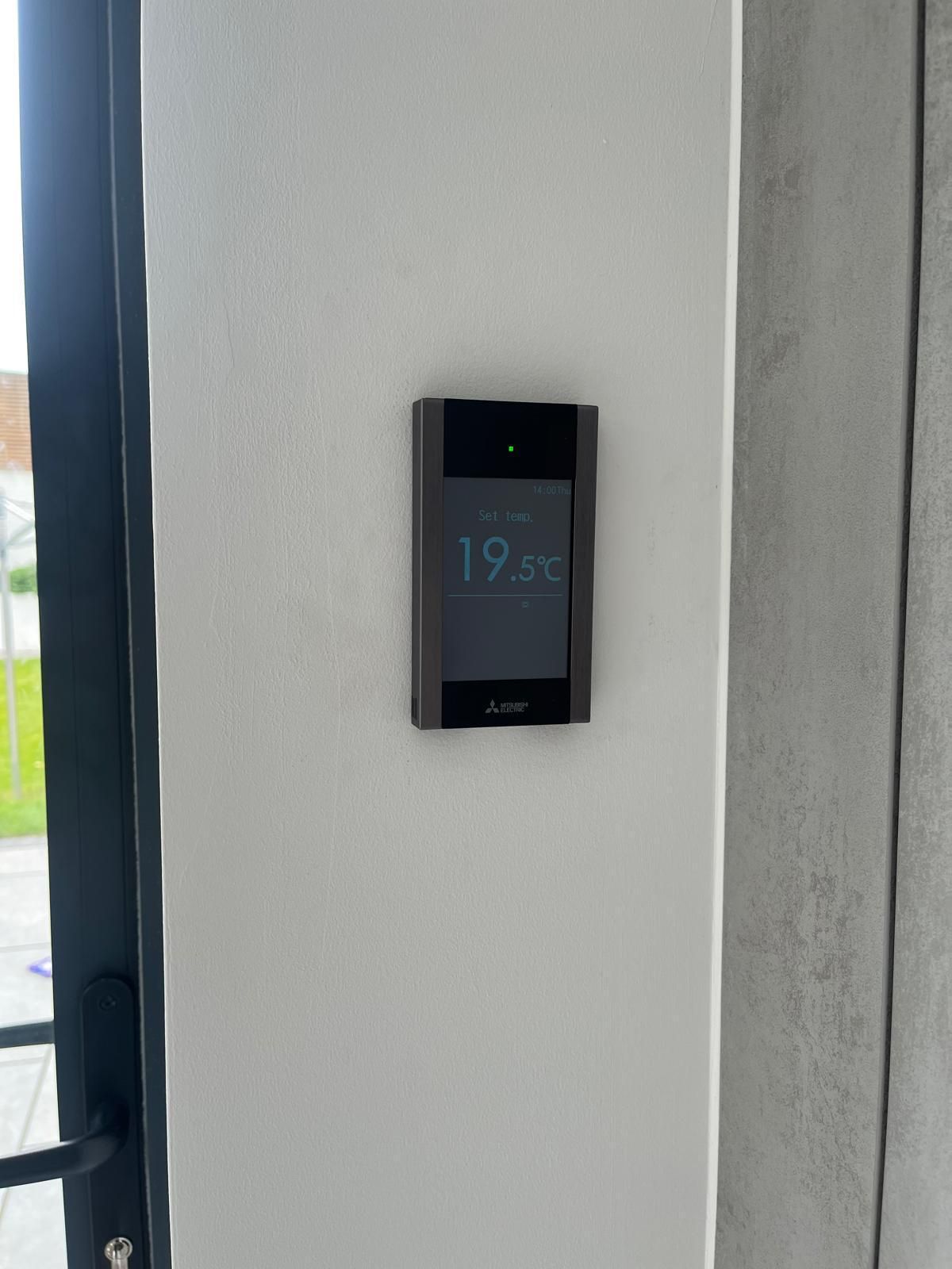 Dark-framed smart thermostat on a white wall, displaying a temperature of 19.3 degrees Celsius.