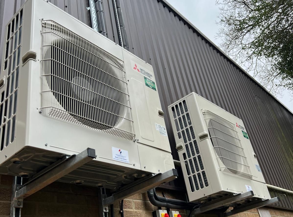 Two white air conditioning units mounted on a building's exterior.