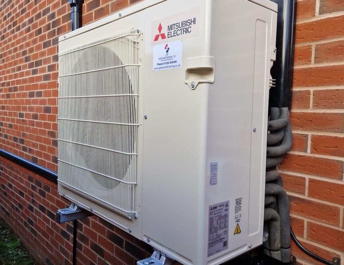 Mitsubishi Electric air conditioning unit mounted on a brick wall.