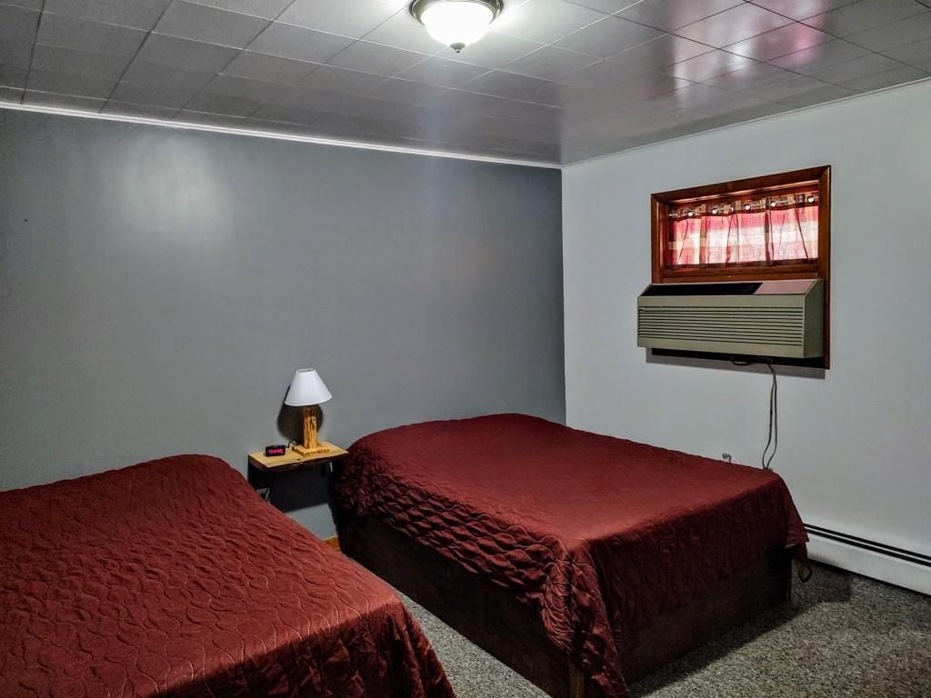 a bedroom with two beds and a window with red curtains